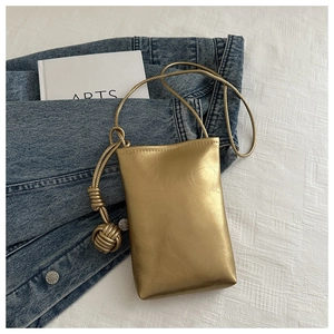 Détail de la pochette de téléphone dorée métallisée avec bandoulière à nœud tressé
