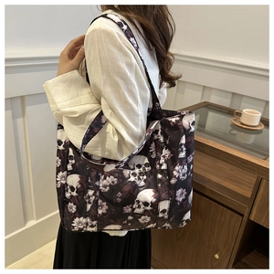 Detail shot of gothic skull and floral print tote bag on model's shoulder