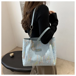 Détail du sac cabas bleu clair avec texture gaufrée et broderie ondulée colorée
