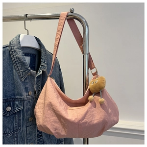 Detail of light pink nylon hobo bag with wide strap and khaki plush doll pendant