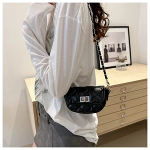 Détail d'un sac bandoulière matelassé noir avec fermoir rotatif argenté et chaîne