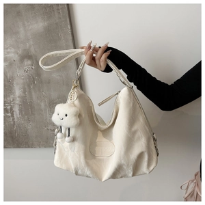 Detail of soft cream leather tote with white cloud plush charm and branded leather patch