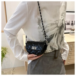Détail du mini sac noir matelassé avec fermoir rotatif argenté porté par le mannequin