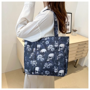 Detailed view of skull and floral print tote bag worn on shoulder in a cozy interior