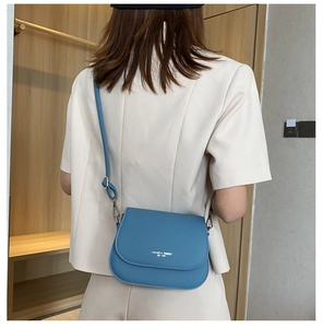 Detail of blue leather saddle bag featuring a flap closure and Fashion Trend logo print