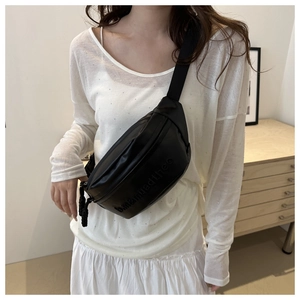 Close-up of minimalist black semi-circle crossbody bag with embossed logo details