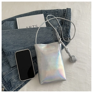 Détail d'un mini sac de téléphone holographique argenté avec nœuds décoratifs sur tissu