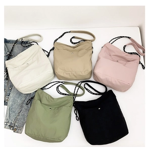 Flat lay of colorful nylon crossbody bags in white, pink, green, khaki, and black colors