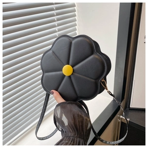 Detail of flower-shaped black crossbody bag with yellow button and gold metal clasp