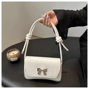 Détail du sac sous l'aisselle en cuir blanc avec boucle nœud argenté et anse nouée