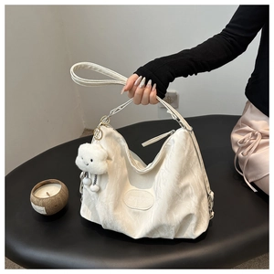Close-up of white pleated PU leather shoulder bag with cute cloud plush charm