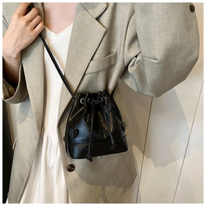 Detail of black drawstring bucket bag with heart-shaped 3D appliqués and long strap