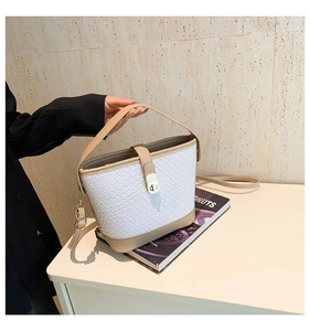 Detail of woven texture bucket bag with adjustable strap and metal twist lock closure
