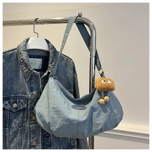 Light blue half-moon hobo bag with fashion label and cute plush monster charm