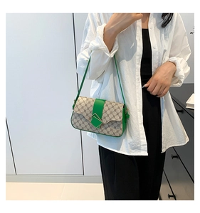 Détail de la bandoulière en cuir vert et de la toile à motif rétro sur un petit sac