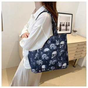 Detail view of large gothic skull floral tote bag with front pocket carried by a model