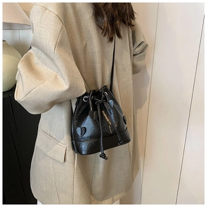 Close-up of black drawstring bucket bag with heart details on a beige blazer