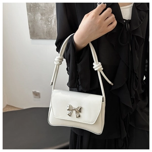 Gros plan sac en cuir verni blanc avec nœud en métal argenté et bandoulière nouée