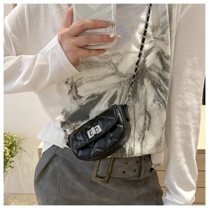 Mini sac bandoulière noir matelassé avec fermoir rotatif et chaîne porté par un mannequin
