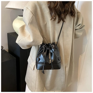 Detail of a black bucket bag with heart-shaped patches and a drawstring closure