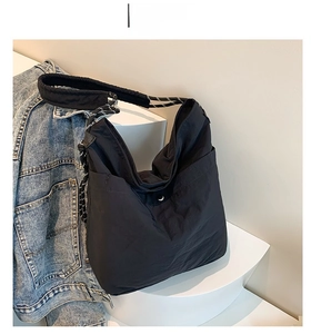 Detail of a black large capacity tote bag with drawstring accents and wide strap