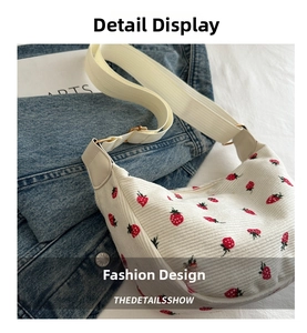 Close-up of white corduroy crossbody bag featuring red strawberry prints and wide strap