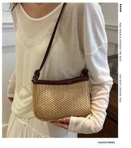 Detail of straw woven crossbody bag featuring dark brown leather trim and slim strap