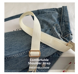 Close-up of beige woven wide shoulder strap with golden metal buckle on denim