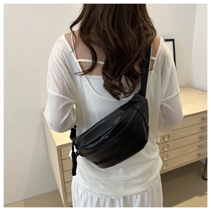 Detail of black PU leather crossbody bag with letter embossing and woven zipper pull