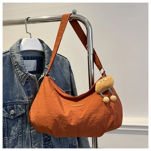 Detail of orange nylon shoulder bag with fashion leather patch and cute cartoon pendant
