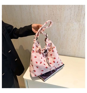 Dettaglio della borsa in velluto a coste rosa con stampe di fragole e chiusura a coulisse