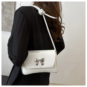 Vue détaillée du sac à bandoulière blanc à nœud sur modèle dans un décor minimaliste