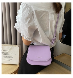 Lavender faux leather saddle bag worn by model in a warm indoor home setting