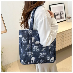 Detail of shoulder tote bag with gothic skull and white floral print in a lifestyle setting