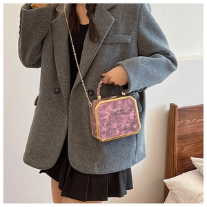 Pink marble hexagonal chain bag with gold metal trim and twisted handle shown on shoulder