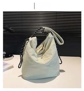 Detail of white nylon tote bag with pleated texture and black-and-white woven handles