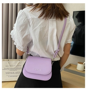Model wearing a lavender saddle crossbody bag with adjustable strap and flap closure