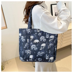 Detail of a dark blue skull and floral tote bag showing front pocket and shoulder strap