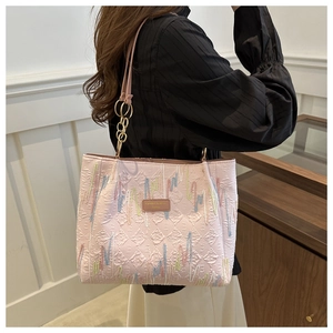 Détail d'un sac cabas rose matelassé avec broderie colorée et patch de marque en cuir