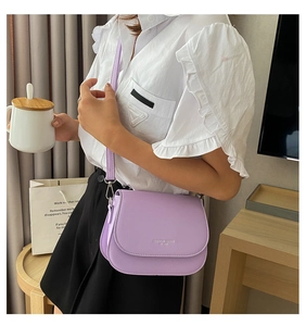 Close-up of a lilac PU leather saddle bag with a silver buckle worn by a model