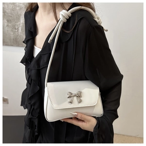 Détail du sac à bandoulière en cuir verni blanc avec boucle nœud argenté et sangle corde