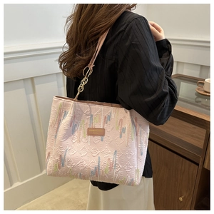 Détail du sac cabas rose avec broderies zigzag colorées et étiquette logo en cuir brun