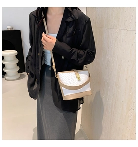 Detail of white woven texture and beige leather trim on a stylish crossbody bucket bag