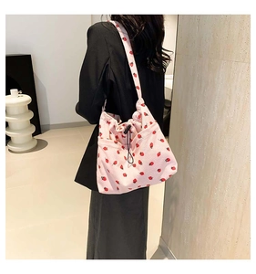 Dettaglio della borsa a spalla in velluto rosa con stampe di fragole e chiusura a coulisse