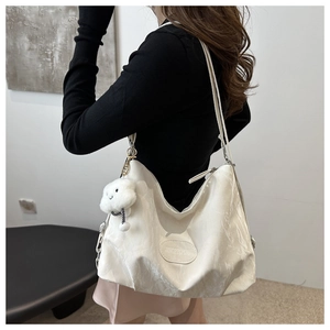 Detail of white pleated faux leather shoulder bag with a cute plush cloud charm