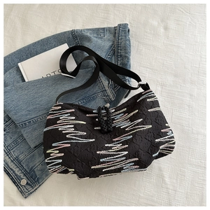 Close-up of black canvas bag featuring colorful wave embroidery and drawstring closure detail