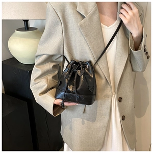 Detail of black drawstring bucket bag with textured heart patches and soft pleated finish