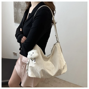 Detailed view of beige tote bag featuring nylon texture, logo plate and cloud pendant