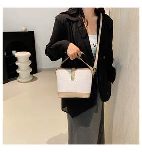 Detail view of woven bucket bag featuring cream leather trim and gold metal clasp