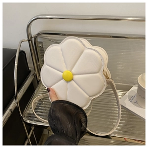 Close-up of white flower-shaped shoulder bag with yellow button and gold zipper detail